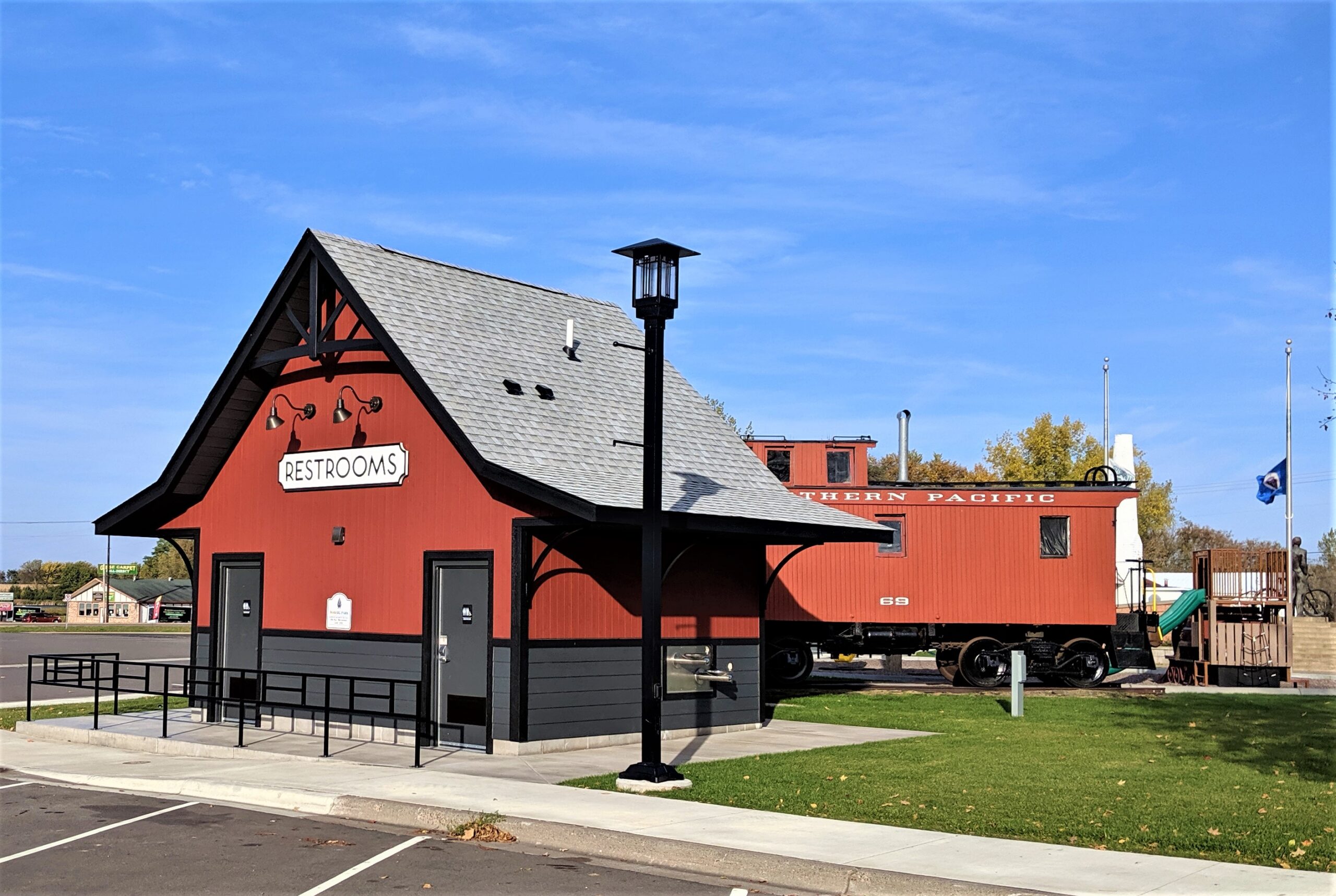 Red restroom building with vintage train car