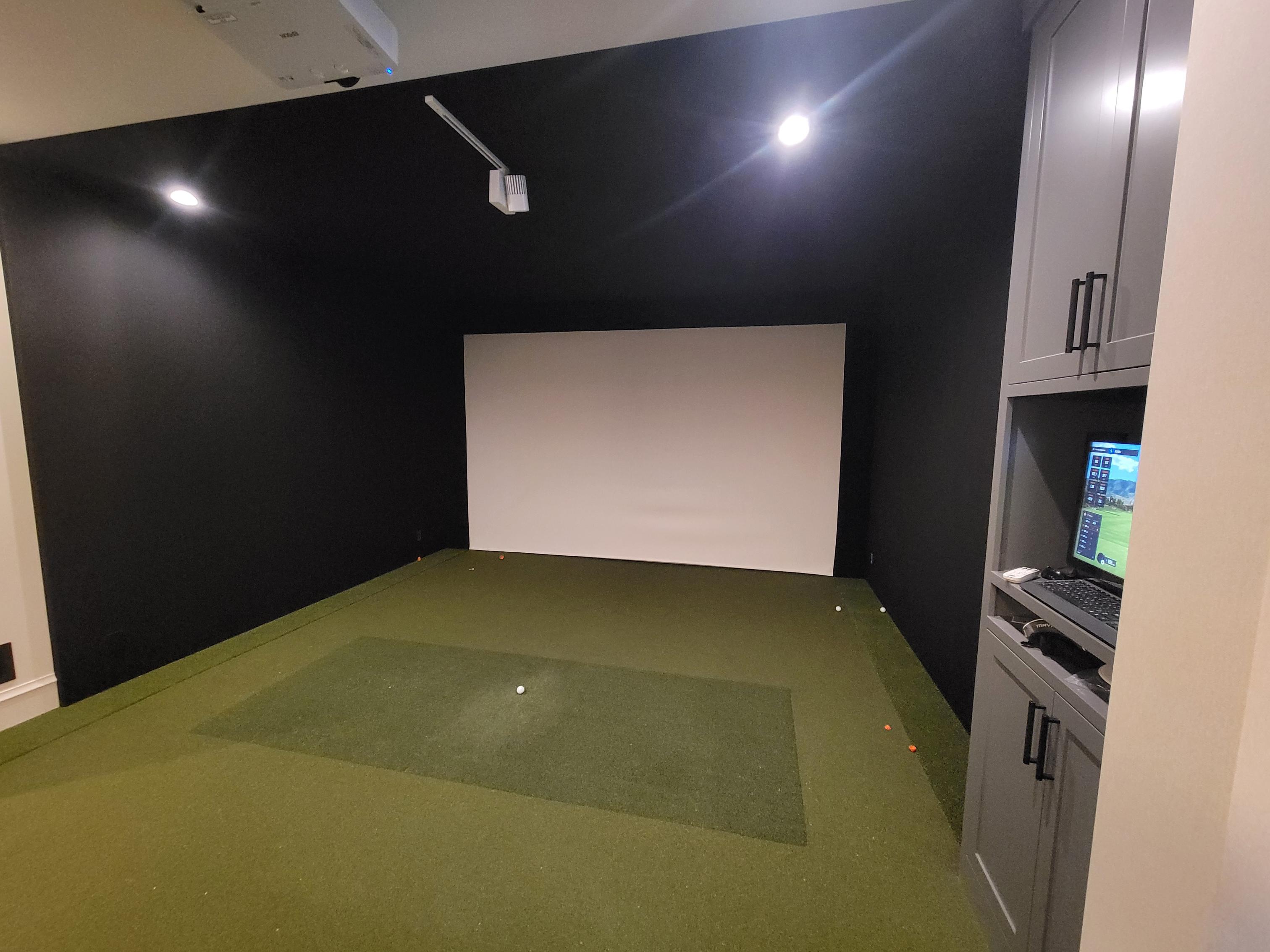 Indoor golf simulator with green turf