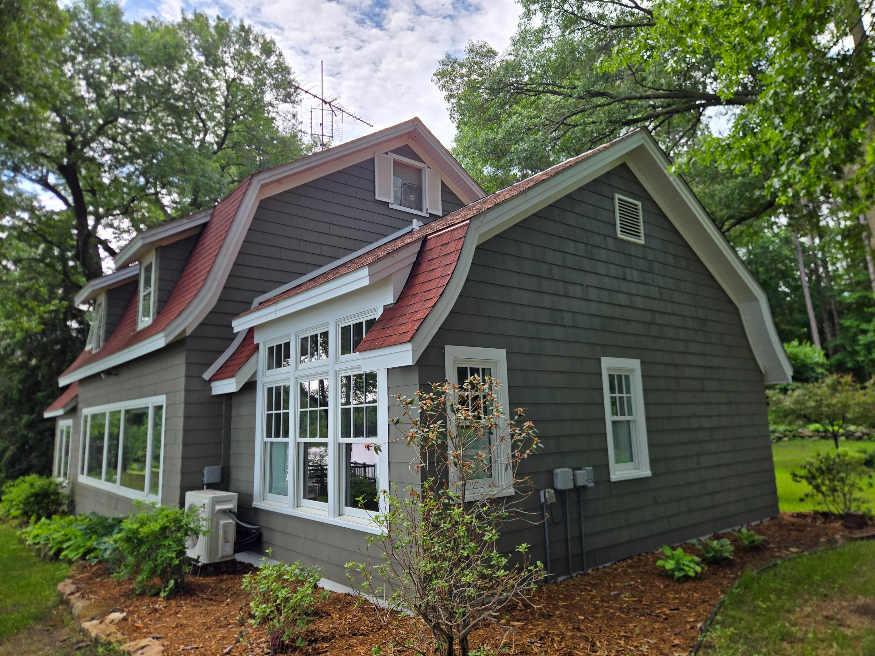 Gray house with red roof among trees