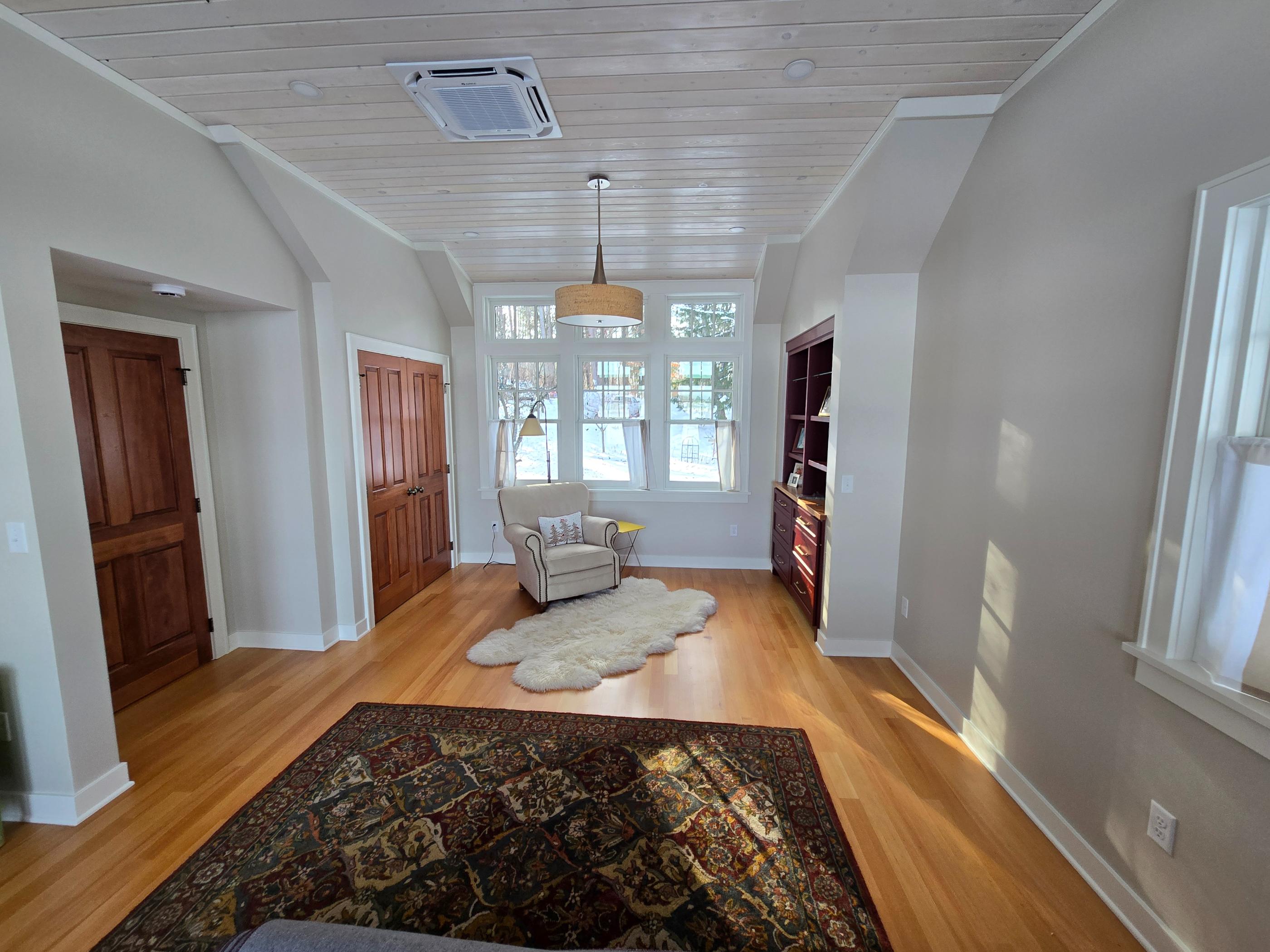 Sunlit living room with armchair and rugs