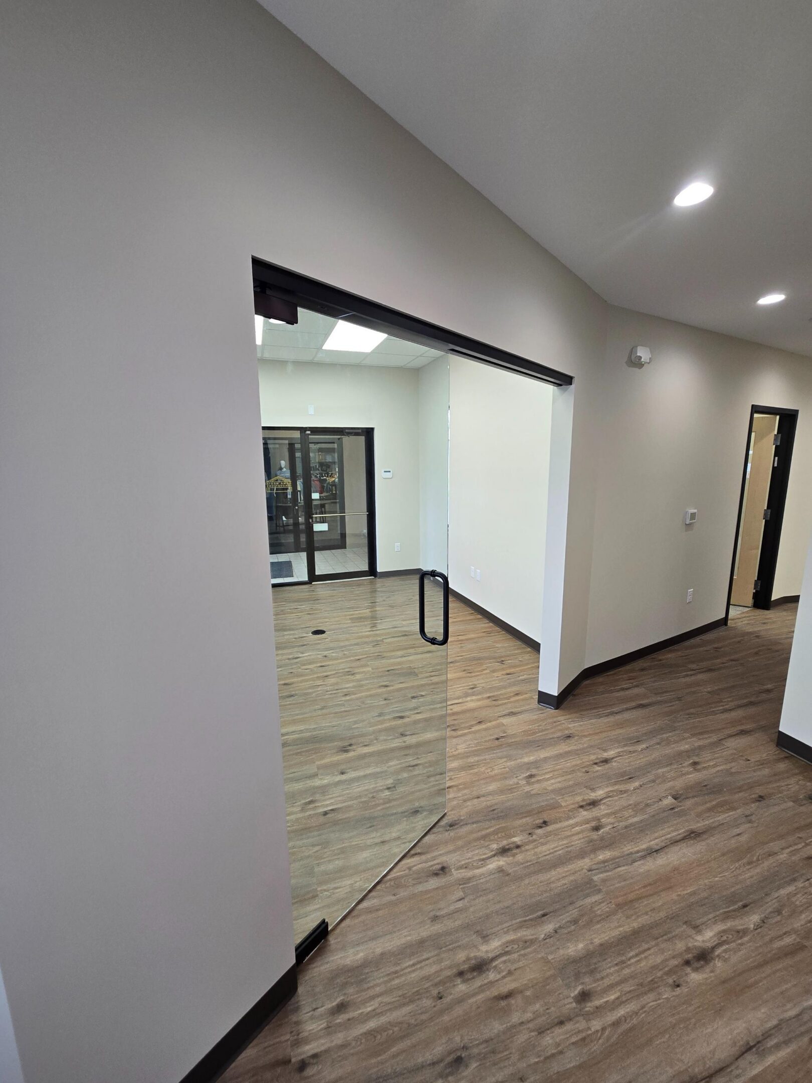 Office hallway with glass door and wood flooring