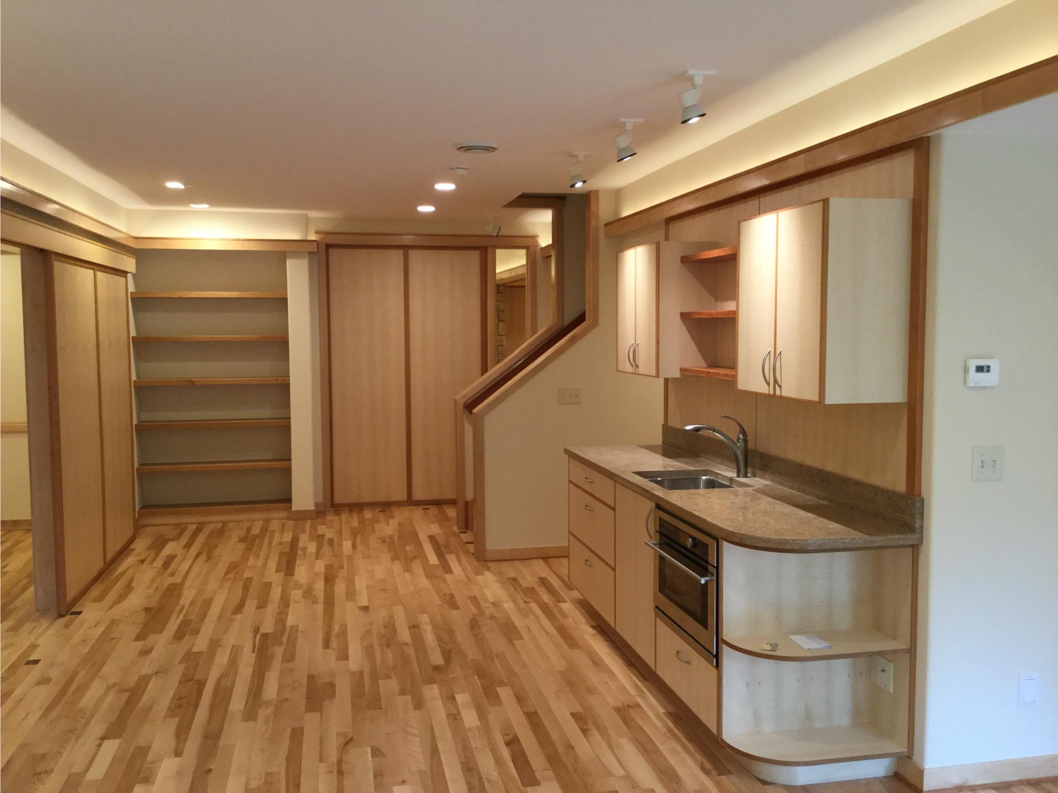 Open-plan basement with kitchenette and wood floors