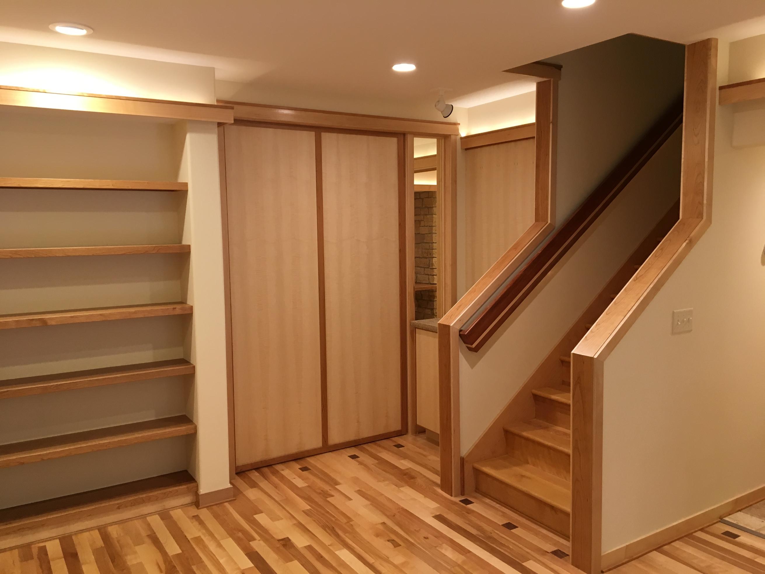 Finished basement with built-in shelves and stairs