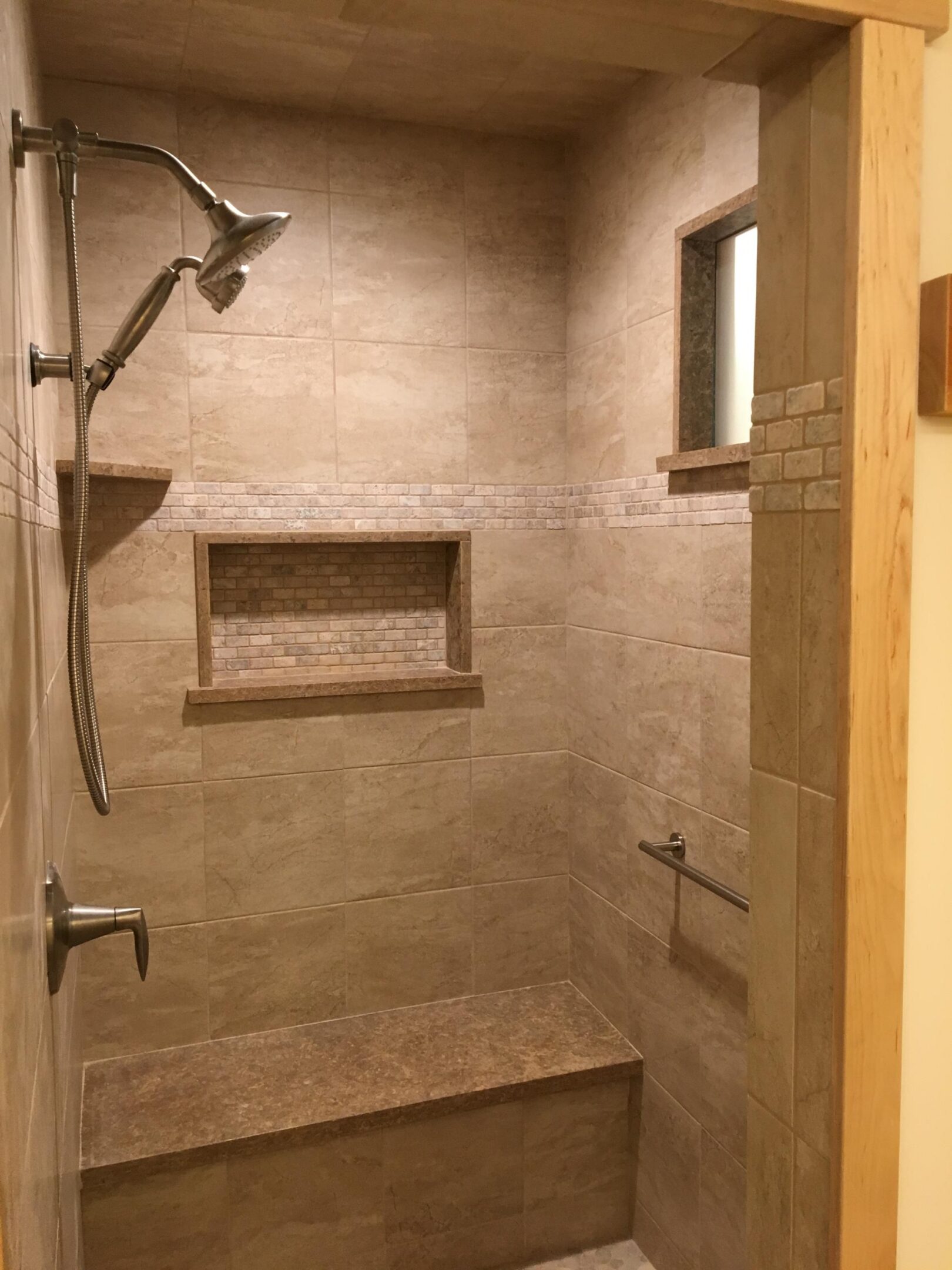 Tiled walk-in shower with bench and niche