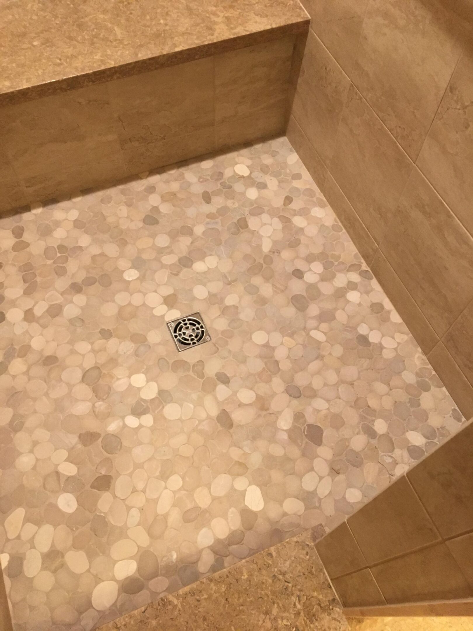 Pebble mosaic shower floor with metal drain