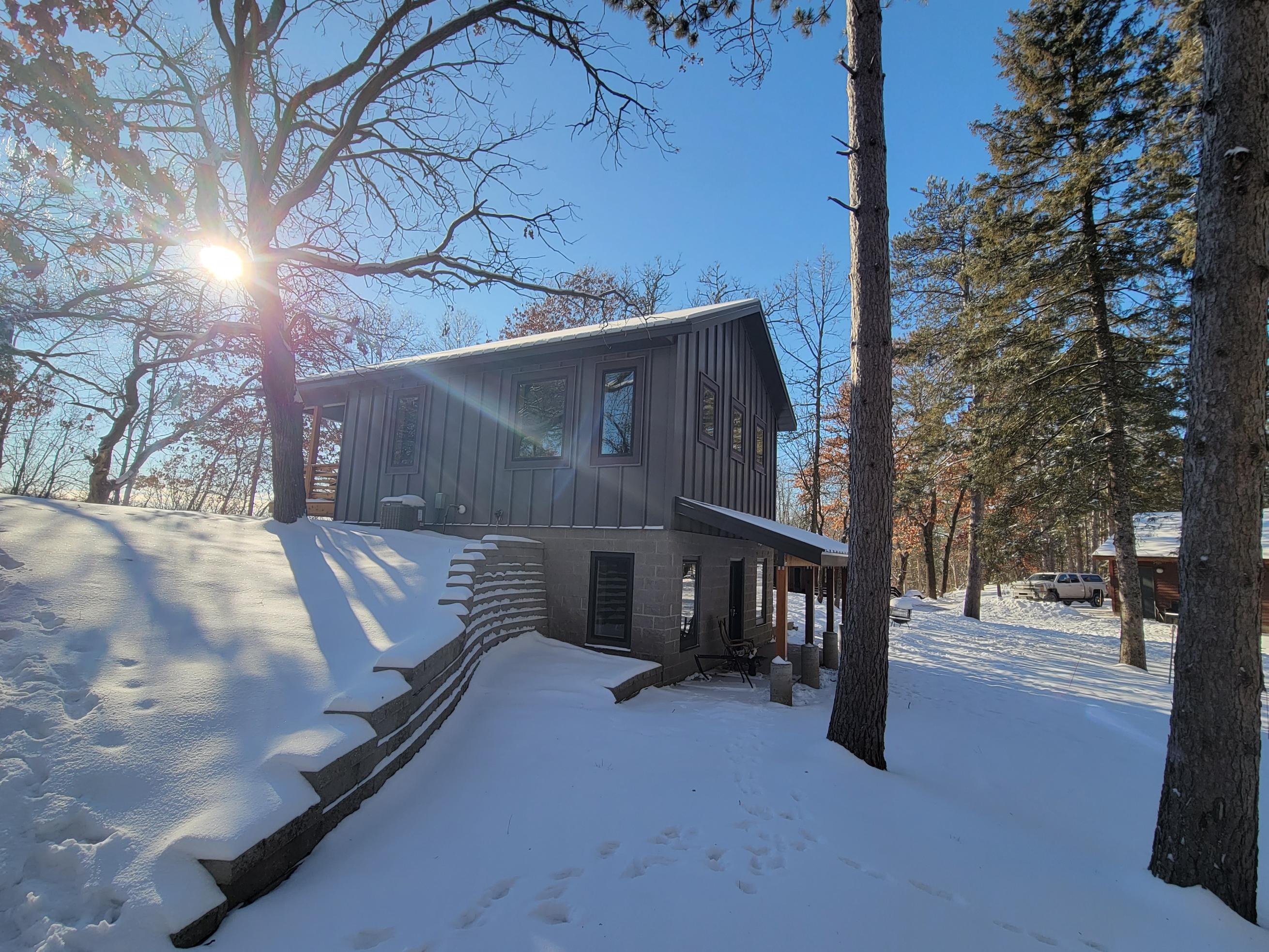Two-story cabin in snowy forest with sun