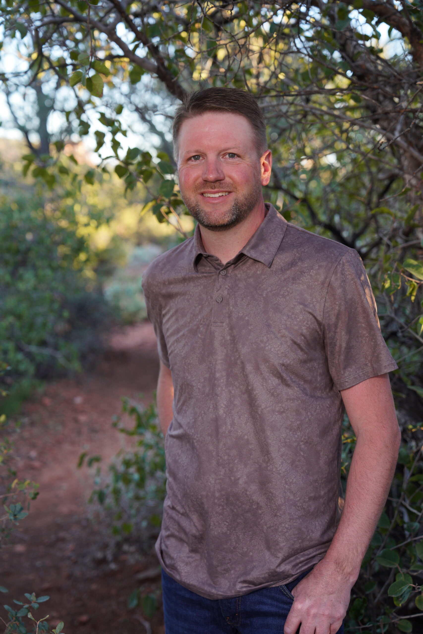 Smiling man standing outdoors among green trees
